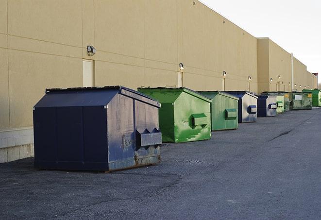 a series of colorful, utilitarian dumpsters deployed in a construction site in Amity